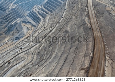 Panoramic view of an open-pit mine with multiple dump trucks transporting minerals