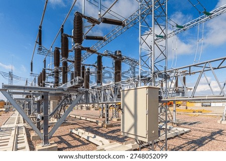 Panoramic view of an outdoor electrical distribution substation, without people, at daytime on a background of a clear blue sky