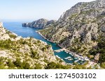 Panoramic view over the calanque de Morgiou on the mediterranean shore near Marseille in the south of France, with its small fishing port and the cap Morgiou in the distance on a sunny spring day.
