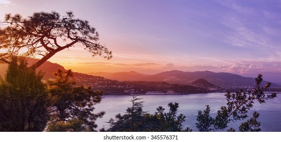 Panoramic view over a coastal town in France, French Riviera, like Canne or Saint Tropez. hills and a bay at sunset - Powered by Shutterstock