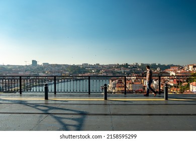 Panoramic View Over The Metro Deck On The Bridge Of - D. Luís I - With One Men Looking From The Side To The Douro River In The Background. City Of Oporto In Portugal.