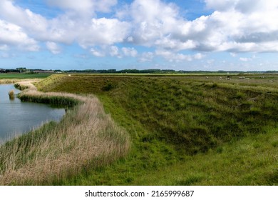 Panoramic view over the moat and bastion or bulwark structure projecting outward at De Schans in Ouddorp, the Netherlands, a 17th century fortress now covered by grass, close to the Grevelingen lake - Shutterstock ID 2165999687