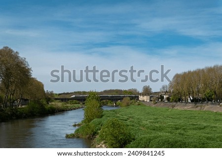 Panoramic view over the river Adour with a bridge in the background over which a fast train passes in the city of Dax in the Basque Country, France
