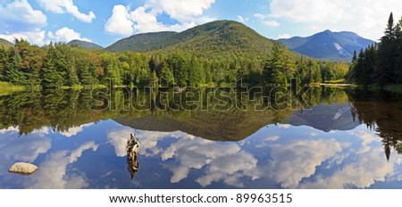 Panoramic view of Phelps Mt, Mt Marcy and Mt. Colden reflected in Marcy Dam Pond in the High Peaks region of the Adirondack Mountains of New York