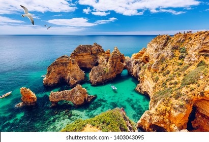 Panoramic view, Ponta da Piedade with seagulls flying over rocks near Lagos in Algarve, Portugal. Cliff rocks, seagulls and tourist boat on sea at Ponta da Piedade, Algarve region, Portugal. 