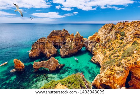 Panoramic view, Ponta da Piedade with seagulls flying over rocks near Lagos in Algarve, Portugal. Cliff rocks, seagulls and tourist boat on sea at Ponta da Piedade, Algarve region, Portugal. 