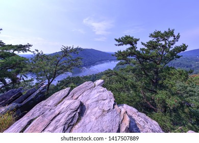 Panoramic View Of The Potomac River Atop Weverton Cliffs On The Appalachian Trail.   A Rocky Outcrop Points Toward The River Below, Surrounded By Evergreens. Scenic Mountaintop View On A Summer Day.