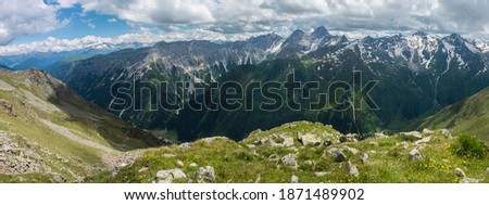 Panoramic view from Pramarnspitze saddle on snow-capped moutain panorama at Stubai hiking trail, Stubai Hohenweg, Alpine landscape of Tyrol Alps, Austria. Summer blue sky, white clouds