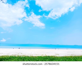 A panoramic view of a pristine beach on a sunny day. The white sand stretches towards the turquoise water, while a vibrant blue sky dotted with fluffy white clouds creates a sense of tranquility. 