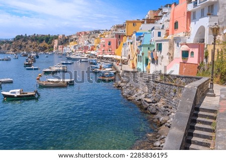 Panoramic view of Procida, Italian Capital of Culture 2022: colorful houses, cafes and restaurants, fishing boats and yachts in Marina Corricella , in Gulf of Naples, Campania, Italy.