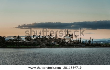 Panoramic view of the revered Hala Sultan Tekke Mosque reflected in the still waters of Larnaca Salt Lake, a significant pilgrimage site in Cyprus.
