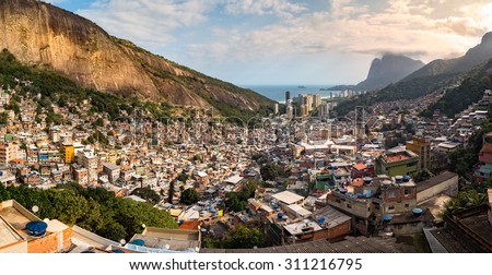 Panoramic view of Rio's Rocinha favela, on a sunny afternoon.  Visible in the distance is the South Atlantic Ocean. The high-rise buildings near the coast are condominiums in Sao Conrado