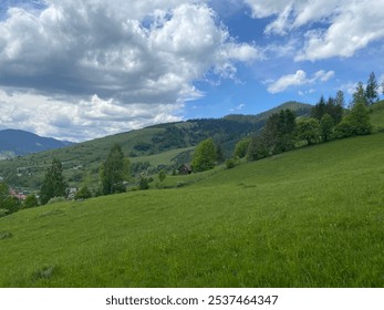 A panoramic view of rolling green hills under a vibrant, partly cloudy sky, showcasing a small cabin nestled within the lush landscape, evoking the peaceful charm of countryside living. - Powered by Shutterstock