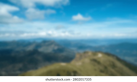 Panoramic view of rolling green mountain ridges stretching into the distance under a clear blue sky with scattered clouds