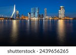 Panoramic view of Rotterdam night time skyline with modern buildings and iconic bridge. Evening sky reflection in River Maas at blue hour with colorful illumination. Major port and big dutch metropole