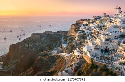 Panoramic view of Santorini. The famous town of Oia in the sunset. A line of sailing yachts at sea. Romantic vacation. Oia, Santorini, Greece