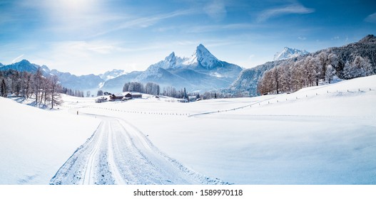 Panoramic view of scenic winter wonderland mountain scenery in the Alps with cross-country skiing track on a beautiful cold sunny day with blue sky and clouds
