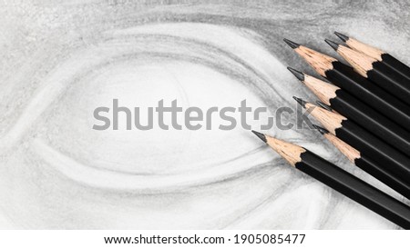 panoramic view of set of black graphite pencils on hand-drawn academic drawing of cast eye close up