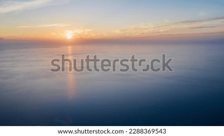 Panoramic view of the setting sun over the vast sea surface. Shot from a drone.