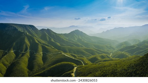 Panoramic view of the Sierra Gorda at sunrise, with lush, vegetation-covered mountains and the sun on the horizon, captured from the air - Powered by Shutterstock