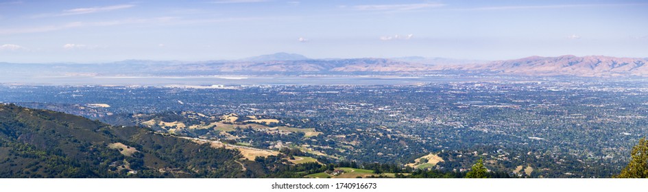 Panoramic view of Silicon Valley, with office buildings close to the bay, surrounded by residential areas; Hills and valleys in Santa Cruz mountains in the foreground; California