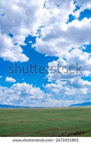 Panoramic view of sky with clouds over green field. Beautiful landscape with fluffy clouds.