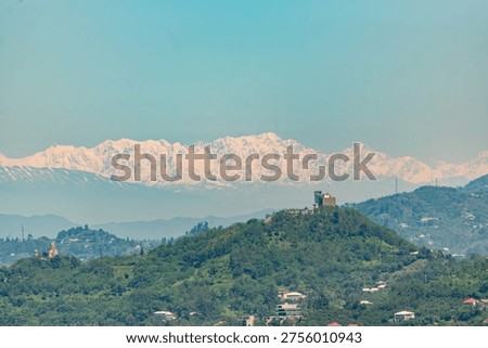 Panoramic view of snow capped Caucasus mountains and green hills under clear blue sky near Batumi Georgia