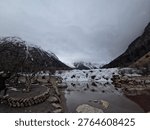Panoramic View of Snow-Capped Mountains Reflected in a Calm Lake under Overcast Sky, Bipenggou, Sichuan, China.	