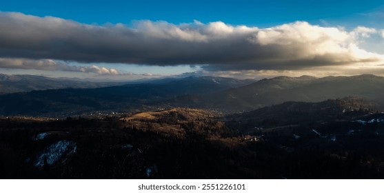 Panoramic view of snow-capped mountains at sunset. The image showcases a picturesque landscape with a clear blue sky, fluffy clouds, and a forest in the foreground - Powered by Shutterstock