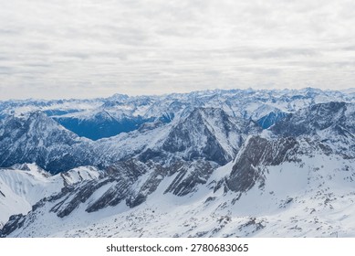 Panoramic view of snow-covered Alpine mountain ranges under a cloudy sky
