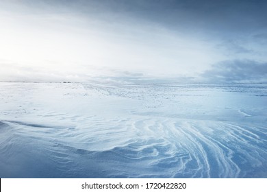 Panoramic view of the snow-covered field after a blizzard at sunset. Human tracks in a fresh snow. Ice desert. Dramatic cloudscape. Global warming theme. Lapland, Finland - Powered by Shutterstock