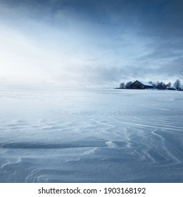 Panoramic View Of The Snow-covered Field After A Blizzard At Sunset. Human Tracks In A Fresh Snow. Old Rustic Wooden House In The Background. Ice Desert. Global Warming Theme. Lapland, Finland