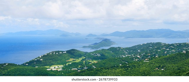 Panoramic view of St. Thomas, US Virgin Islands. Lush green hills, scattered villas and the vast Caribbean Sea with distant islands under cloudy tropical skies