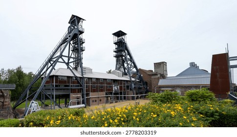 Panoramic view of steel mining headframes and museum buildings with flowerbed at Bois du Cazier, Marcinelle, Charleroi, Belgium.