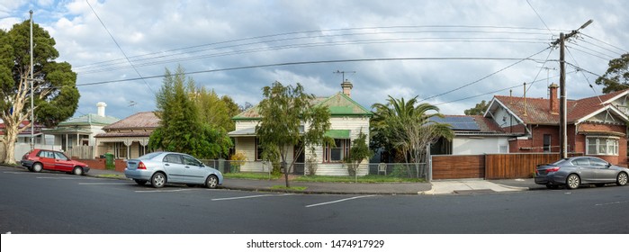 Panoramic view of suburban residential houses in Melbourne. Quiet neighbourhood street with homes, family cars and trees along pedestrian walkway. VIC Australia.