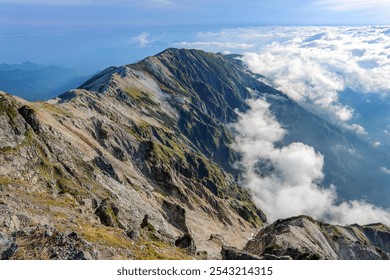 Panoramic view of a sunlit mountain range with rolling hills and lush greenery above a sea of clouds - Powered by Shutterstock