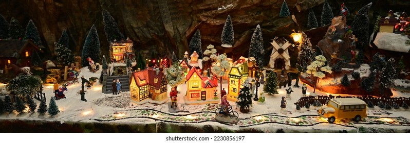 Panoramic view of a tabletop Christmas village with miniature figurines and snowy trees - Shutterstock ID 2230856197