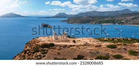 Panoramic view of the Temple of Poseidon at Cape Sounion at the edge of Attica, Greece, with moored sailboats in the bay during summer time