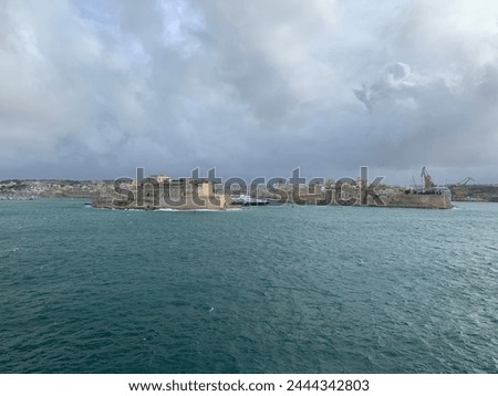 Panoramic view of three cities (Birgu (Vittoriosa), Bormla (Conspicua), Senglea) skyline with St. Angelo fort. Heavy Mediterranean sea waves at Grand harbour. View from Valletta, Malta