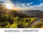 A panoramic view of the Three Sisters rock formation in the Blue Mountains, Australia. The photo was taken from the scenic Echo Point Lookout with a railing overlooking the vast landscape.