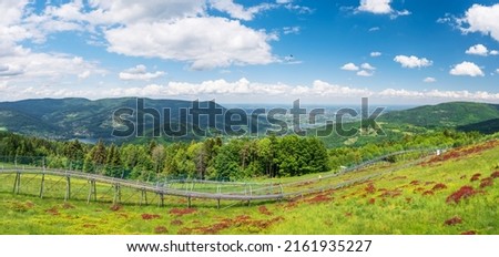 
Panoramic view from the top of the heat towards the north. The summer toboggan run . Lake Czanieckie and the Międzybrodzkie in the background. View of the Silesian Beskids and the Little Beskids. 