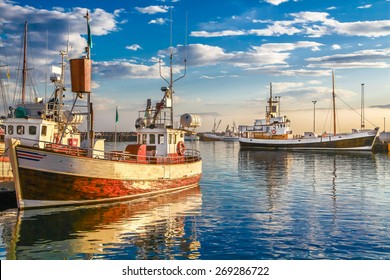 Panoramic view of traditional old wooden fisherman boats lying in harbor in beautiful golden evening light at sunset, town of Husavik, Skjalfandi Bay, Iceland, northern Europe