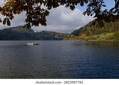 Panoramic view of a tranquil lake surrounded by autumn hills under a partly cloudy sky. Autumn Landscape in Swiss Alps. Tuerlersee in Canton of Zurich, Switzerland.