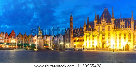 Panoramic view of typical Flemish colored houses and statue of Jan Breydel and Pieter de Coninck on the Grote Markt or Market Square during evening blue hour, Bruges, Belgium