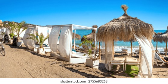 Panoramic view of typical straw umbrellas and sunshade  white sunshade tents on beach at Benalmadena's coast. Malaga province, Costa del Sol, Andalusia, Spain