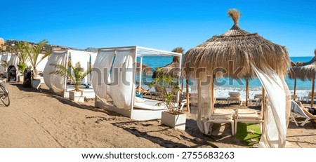 Panoramic view of typical straw umbrellas and sunshade  white sunshade tents on beach at Benalmadena's coast. Malaga province, Costa del Sol, Andalusia, Spain