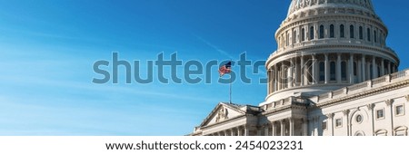 Panoramic view of the United States Capitol dome with its flag against a blue sky.