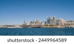 A panoramic view of USS Midway museum from the bay of San Diego, with buildings and architecture in the background, sunny winter morning