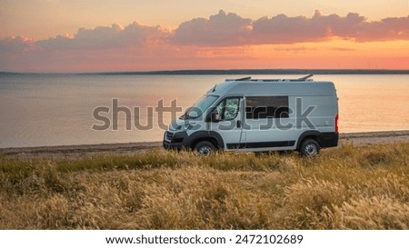 panoramic view to white camper van on the coast in calm morning before sunrise