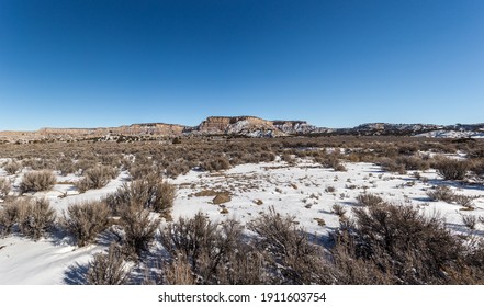 Panoramic View Of Wide Open Desert Vista Covered In Snow With Mountain Range On Clear Day In Rural New Mexico